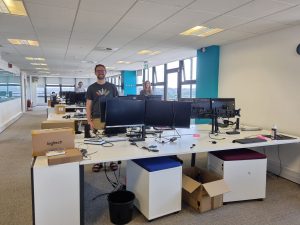 Office with desks, computers and three staff members.