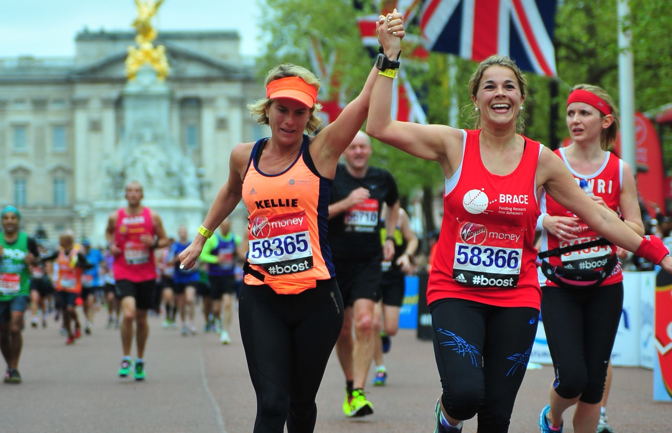 Two women holding hands and running towards the end of the London Marathon