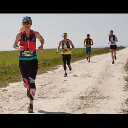 A woman is running on a path with three runners behind her.