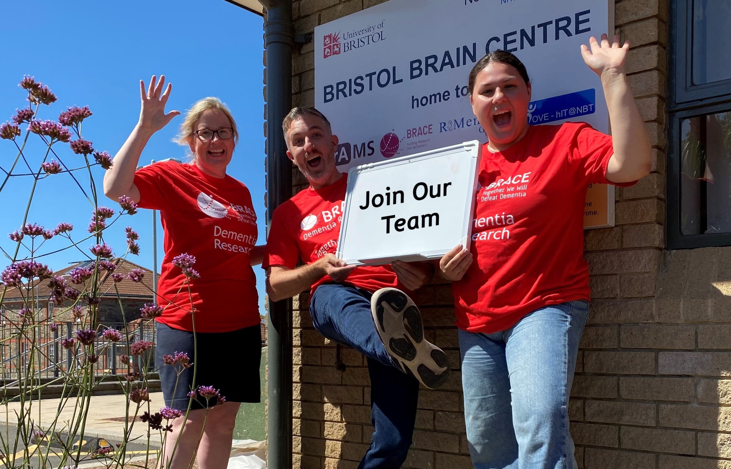 BRACE Fundraising Four people are stood outside the Bristol Brain Centre. The are all wearing BRACE red t-shirts.