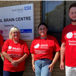 Four people are stood outside the Bristol Brain Centre. The are all wearing BRACE red t-shirts.