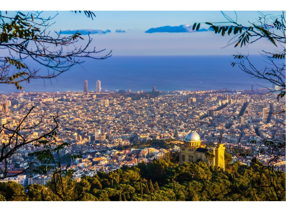 A sunny panorama view of the city of Barcelona. In the distance is the blue sea and sky.
