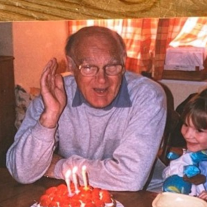 Grandad and Elise sat to a table with a birthday cake.