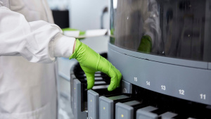 Hands taking equipment from a lab machine.