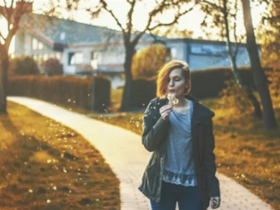 A woman is blowing a dandelion.