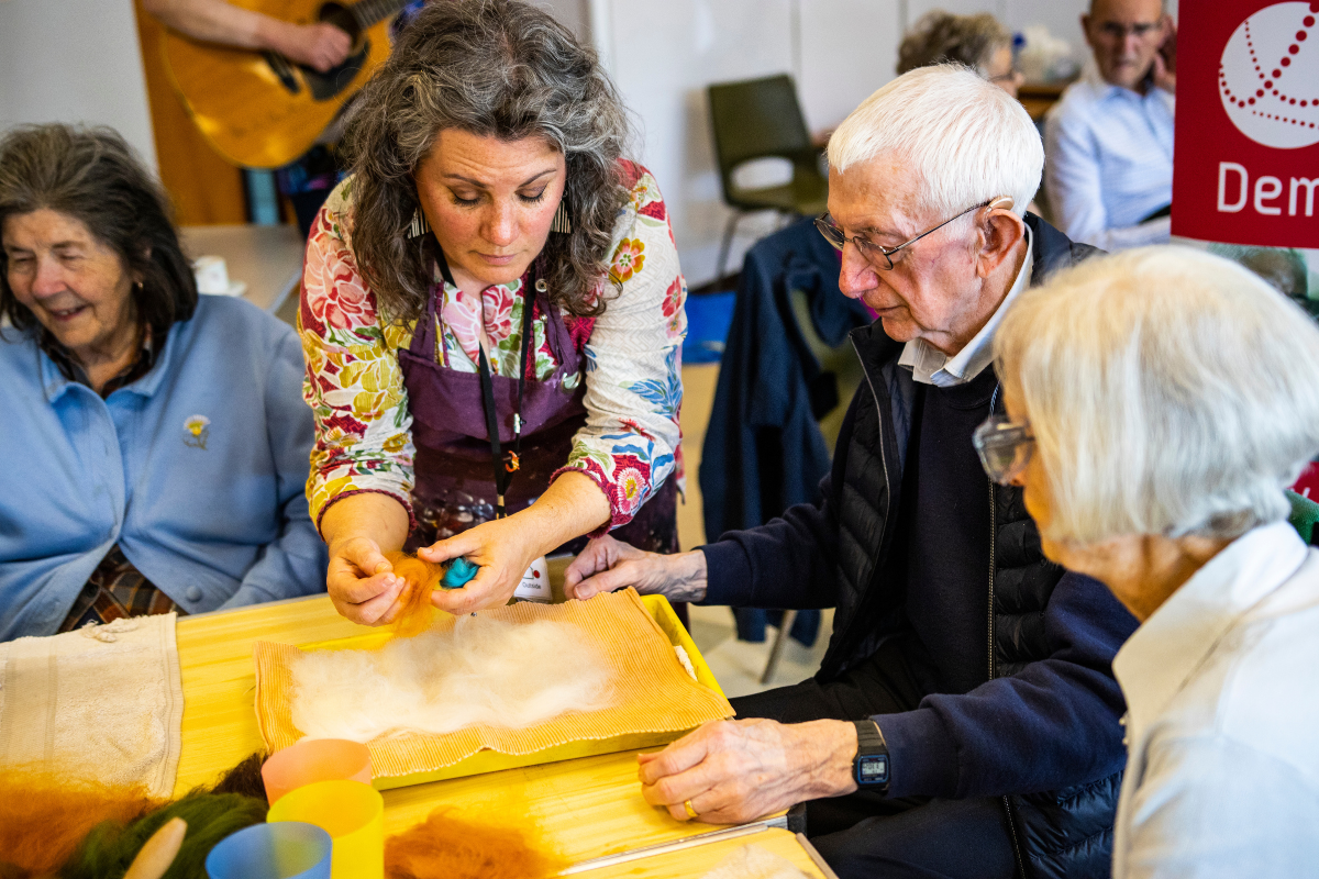 A woman teaches a man how to make felt art.