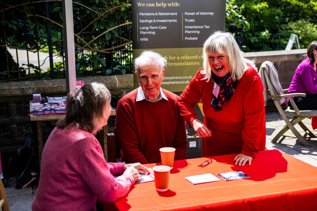 A group of people talk and laugh while sat around a table.