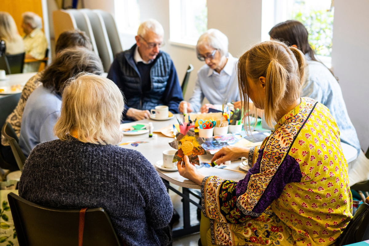 A group of people are sat around a table making art.