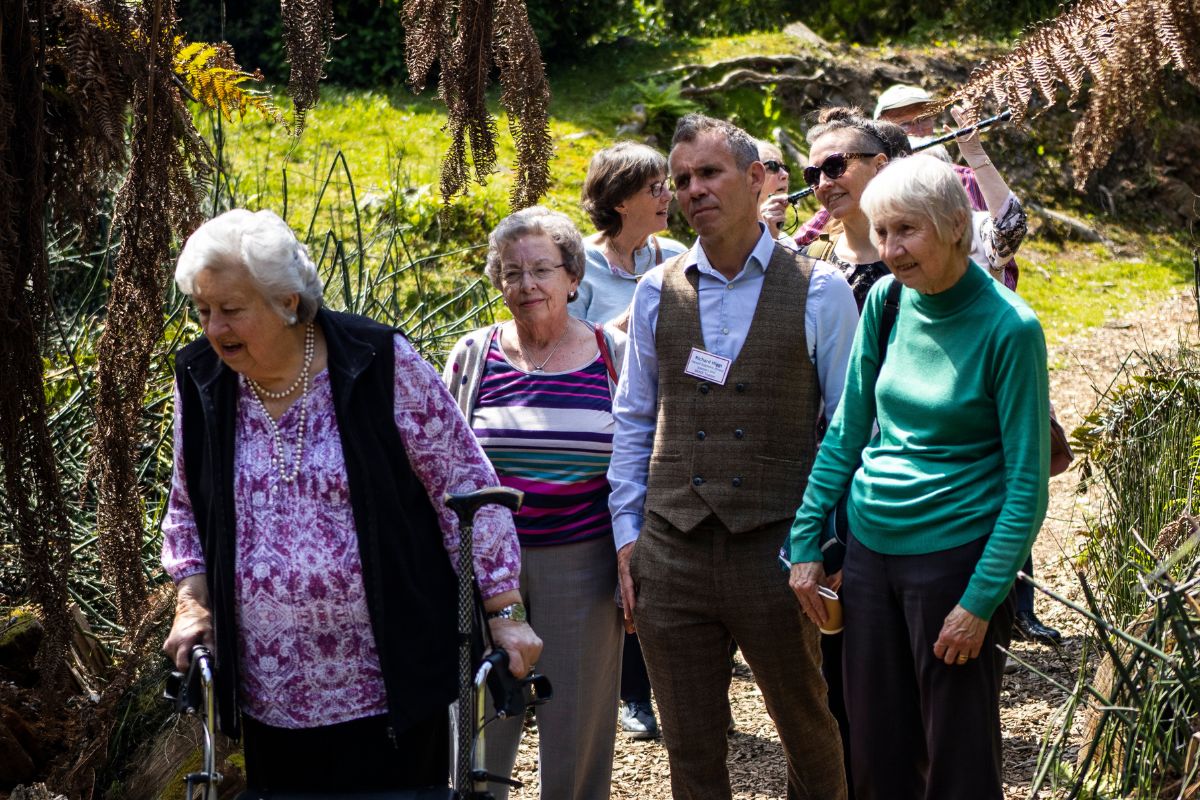 A group of people look at plants while on a tour of the UOB Botanic Gardens.