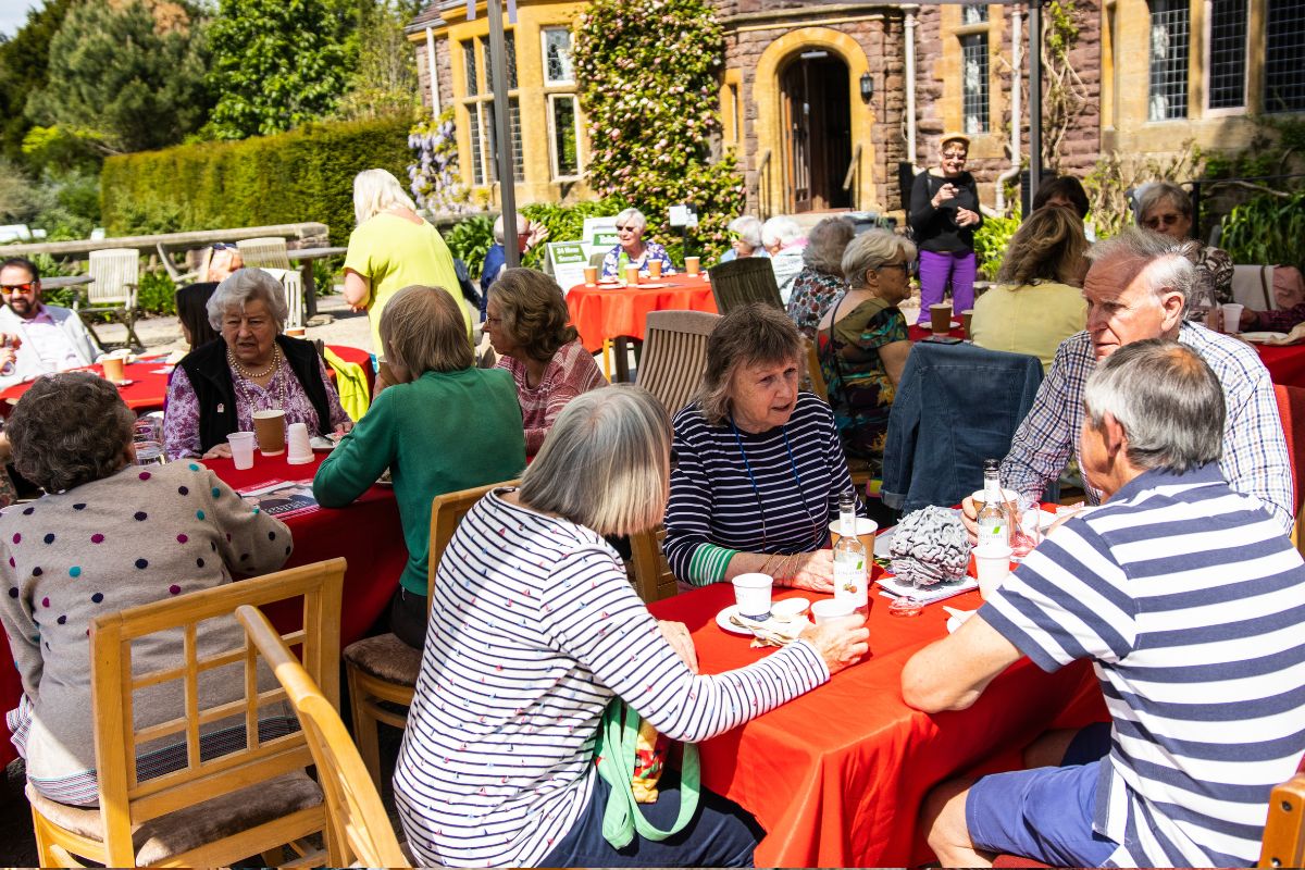 Many groups of people have a conversation sat around a table with lunch.