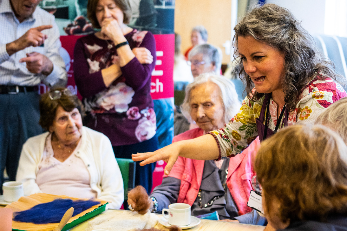 A woman teaches a group of people how to make felt art.