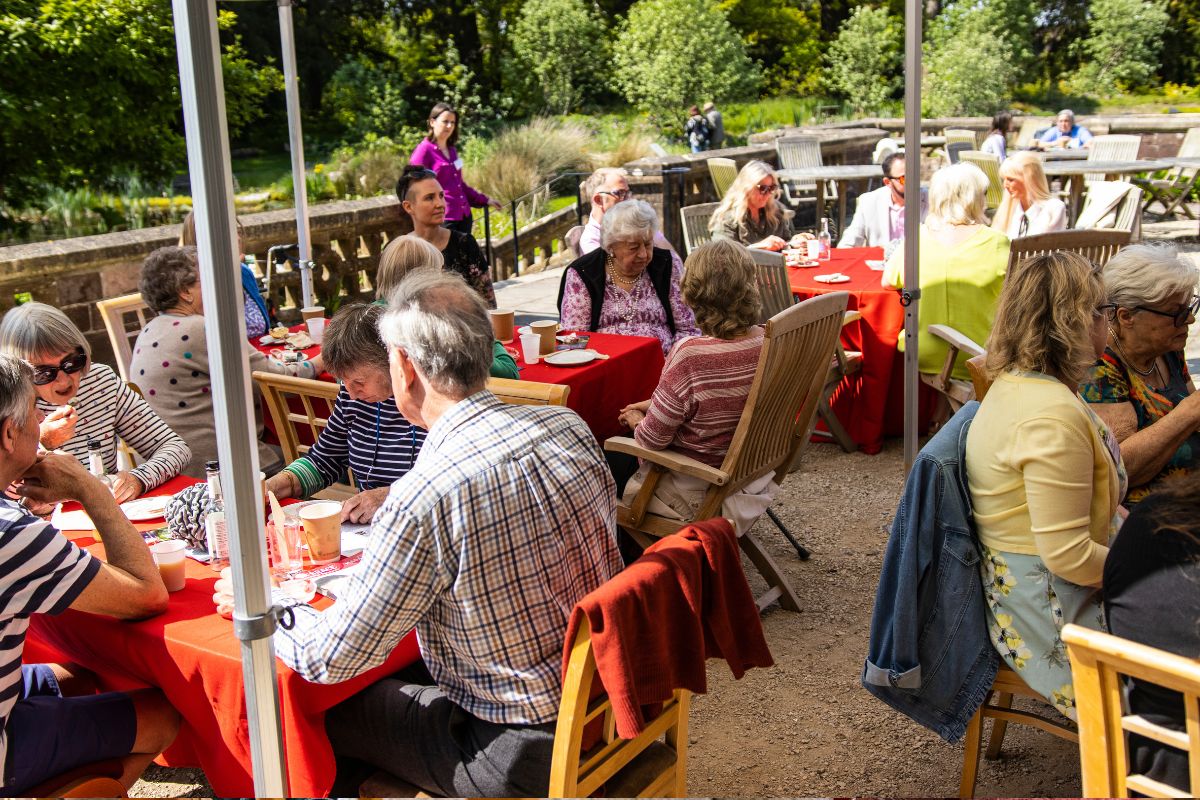 Many groups of people have a conversation sat around a table with lunch.