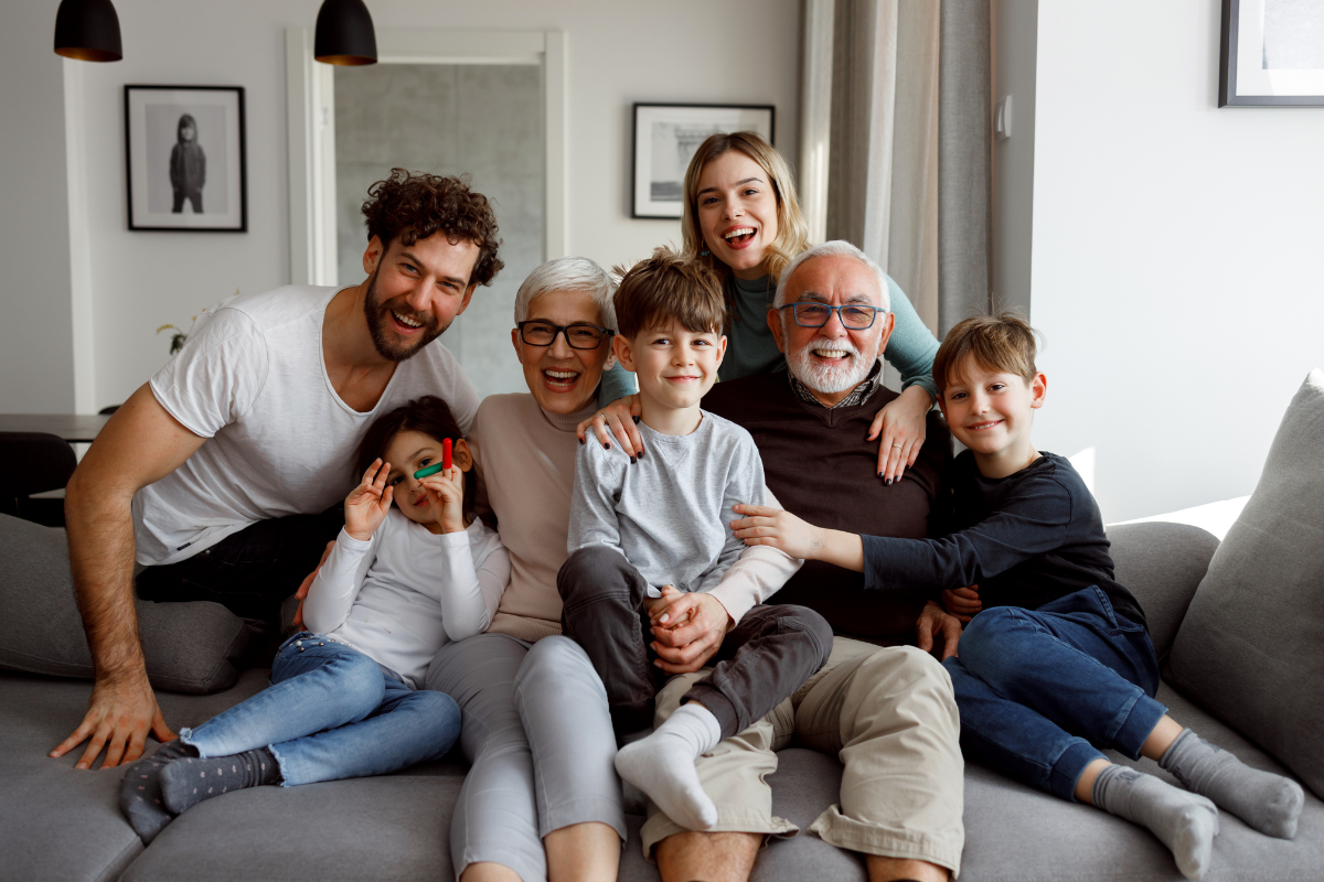 Grandparents, children and grandchildren all sat on a sofa.