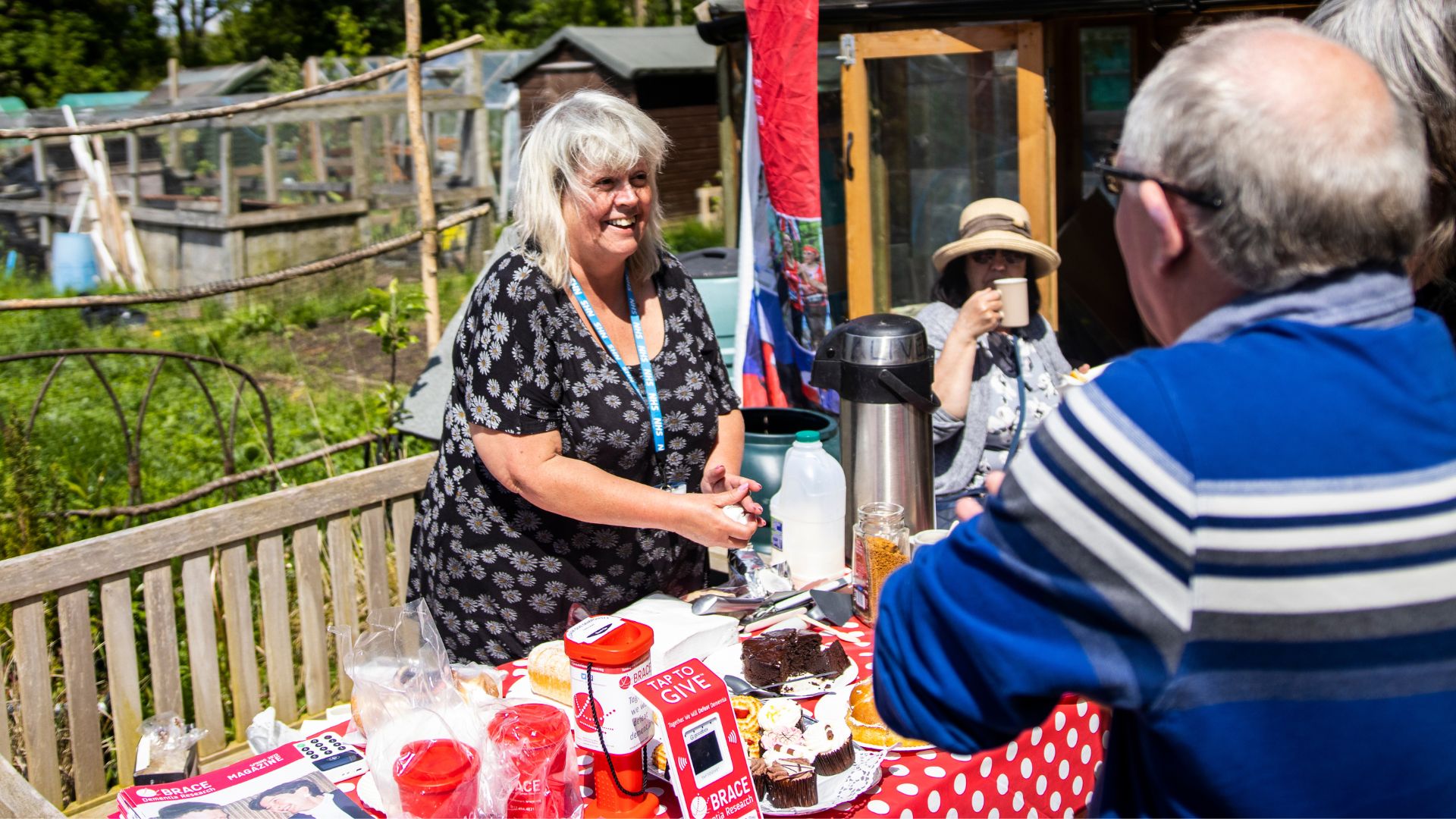 A woman and a man have a conversation while she makes mugs of tea and coffee.