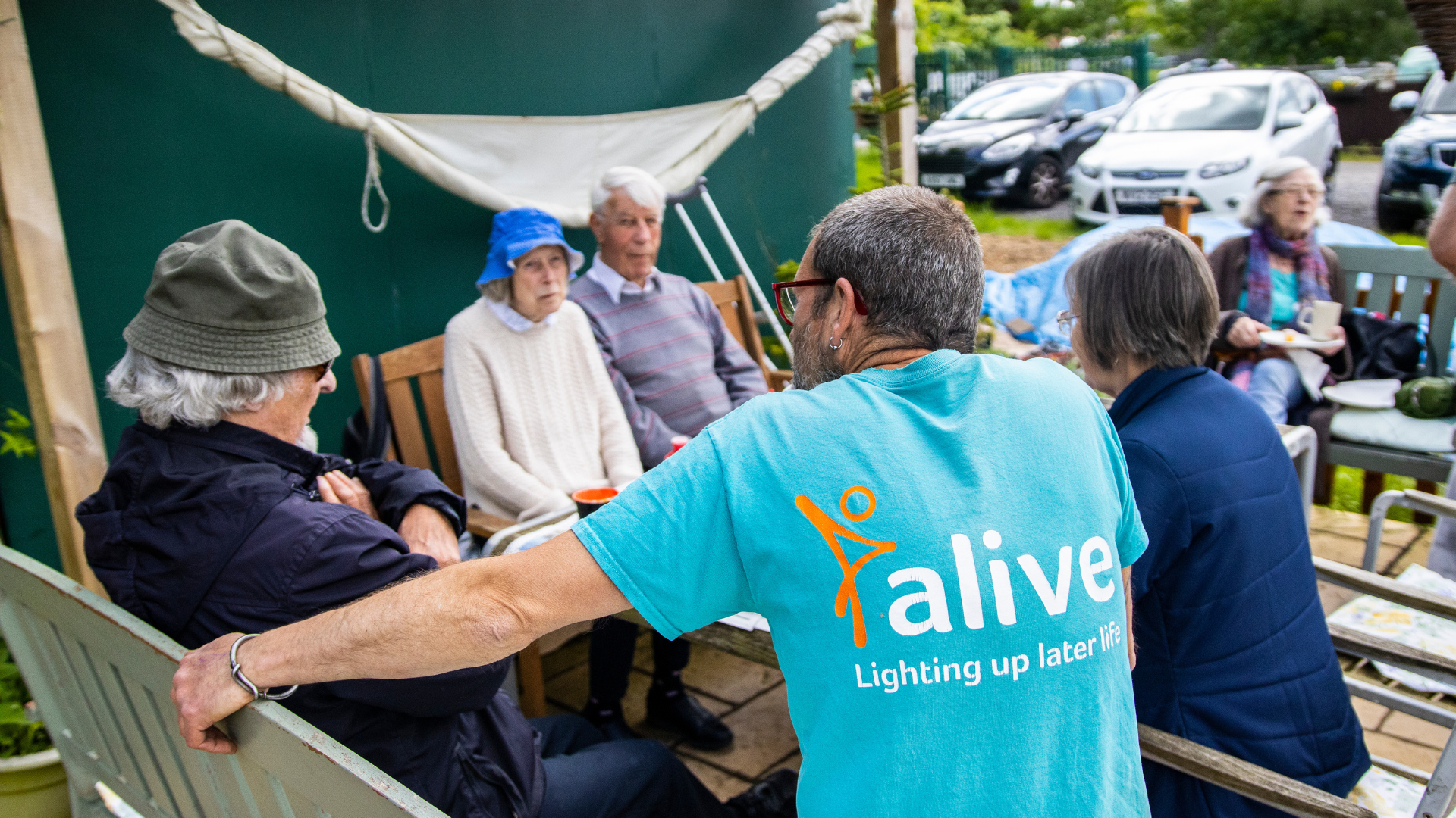 People are sat around a table at the Alive Allotments Dementia Friendly Garden.