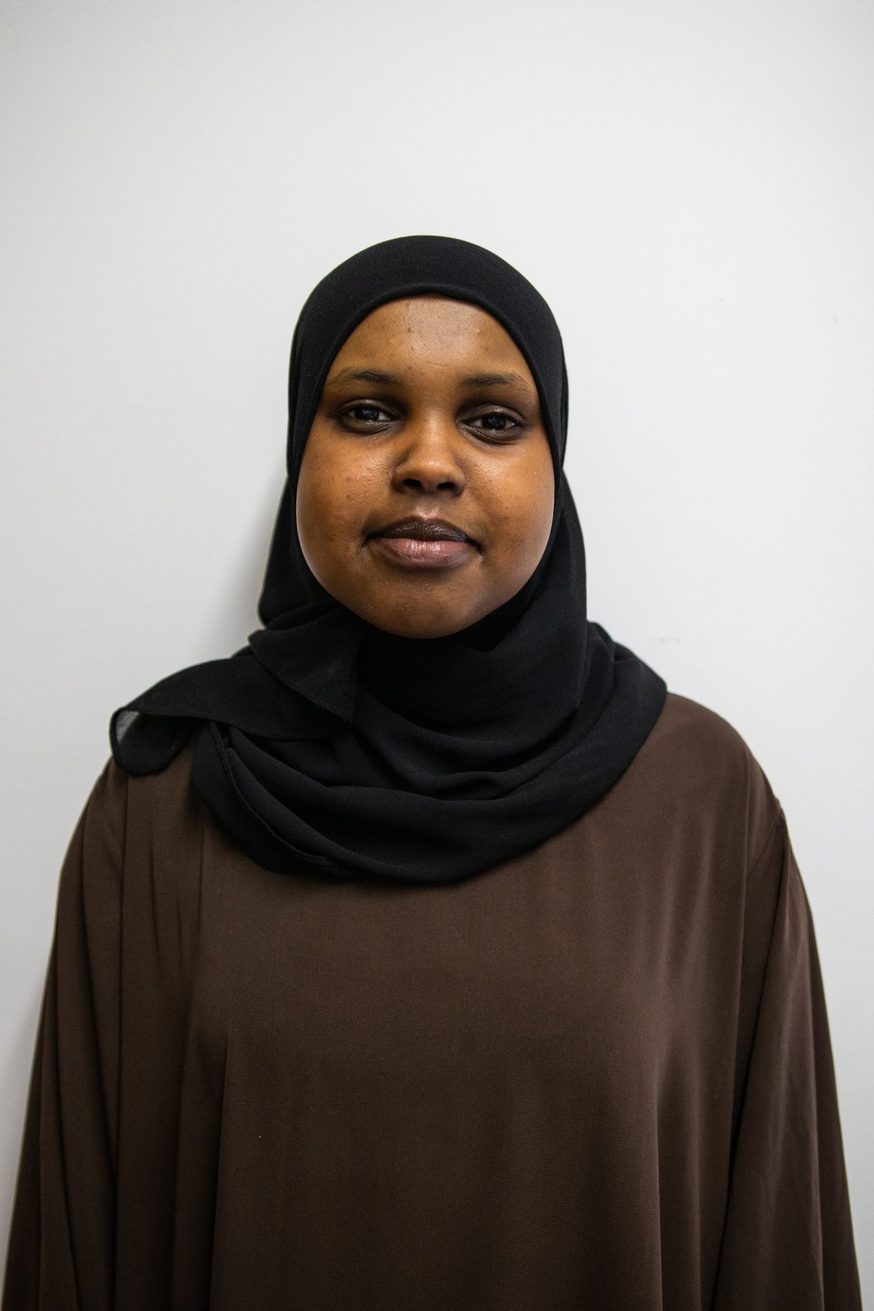 A headshot of Ugbad. She is a POC woman in her early 20s, she is wearing a hijab.