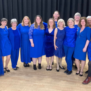 Avon Harmony Choir, the singers are all woman and wearing royal blue dresses.