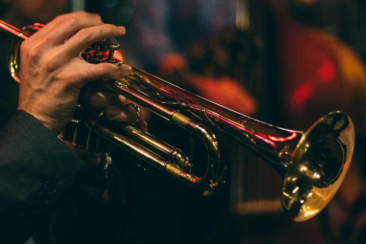A trumpet is being played, only the hands of the player can be seen.