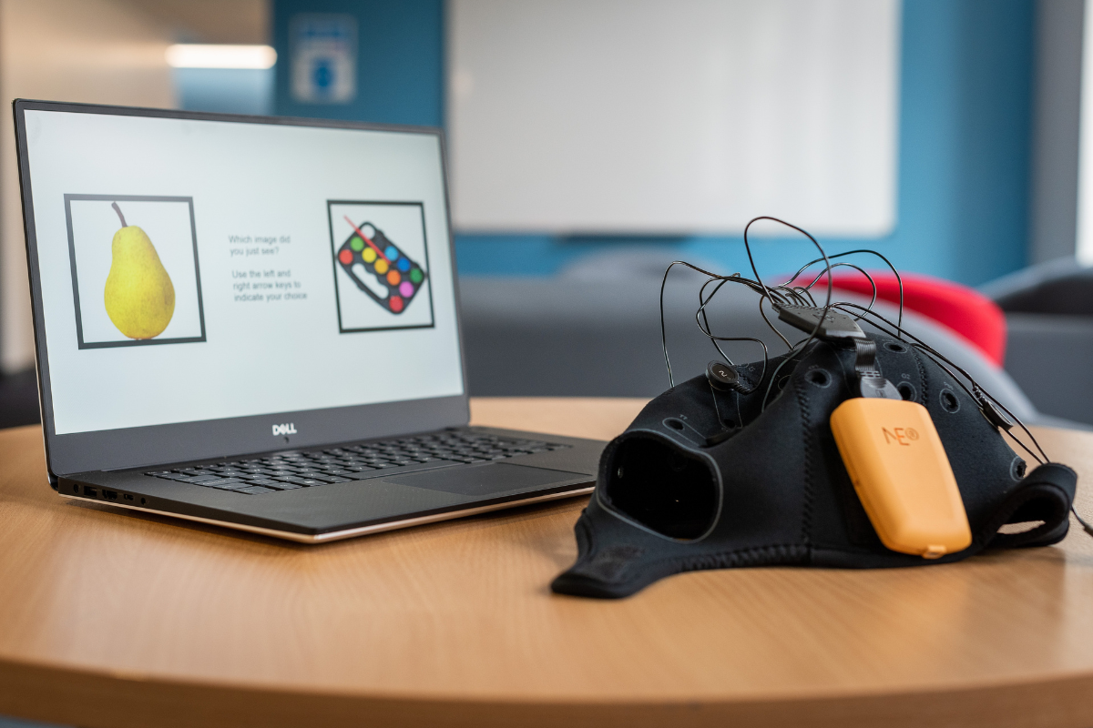 A laptop on a desk with the Fastball cap next to it.