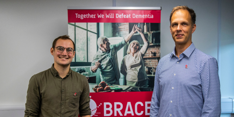 PhD student Oliver Hermann and researcher George Stothart standing next to a BRACE banner.