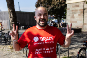 A runner at the Bristol half marathon wearing a red BRACE top, doing peace signs with both hands.