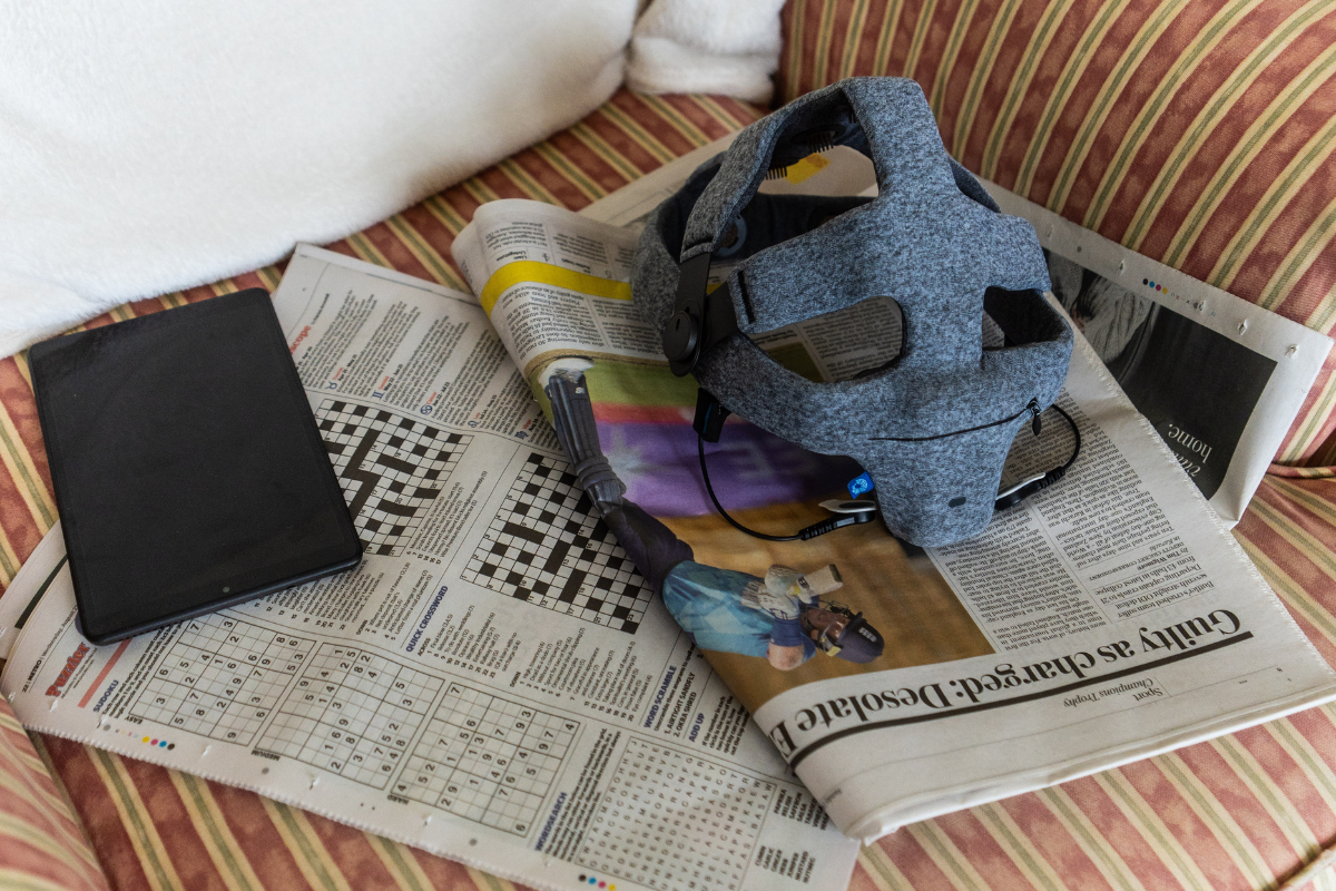 The Fastball cap and tablet are on top of newspapers, on the seat of an armchair.