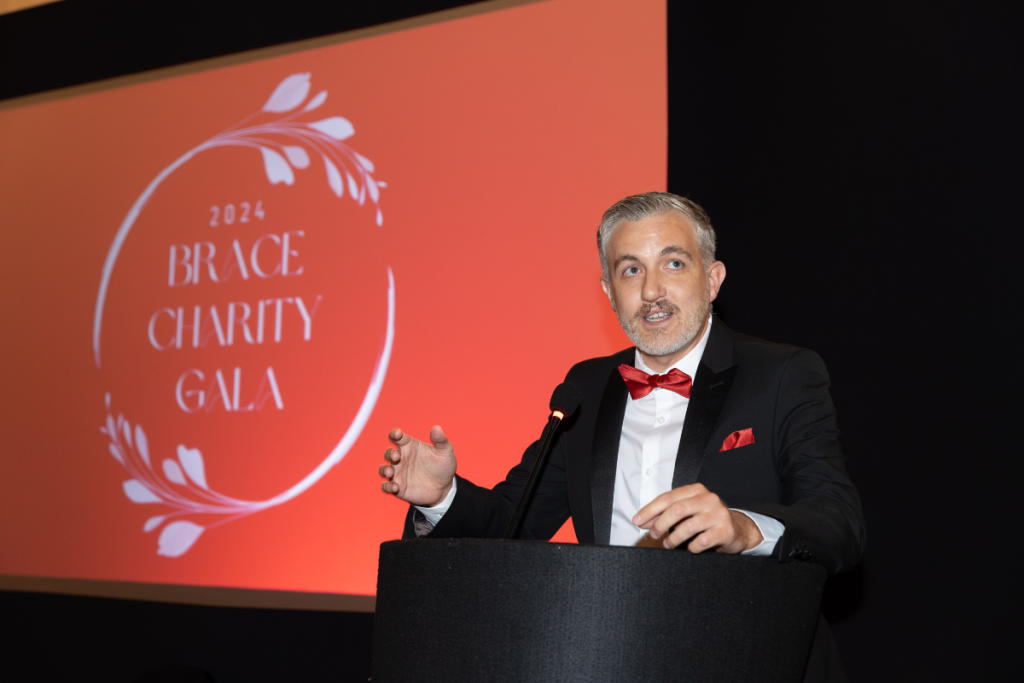 Chris Williams is stood to a lecturn giving a speech.