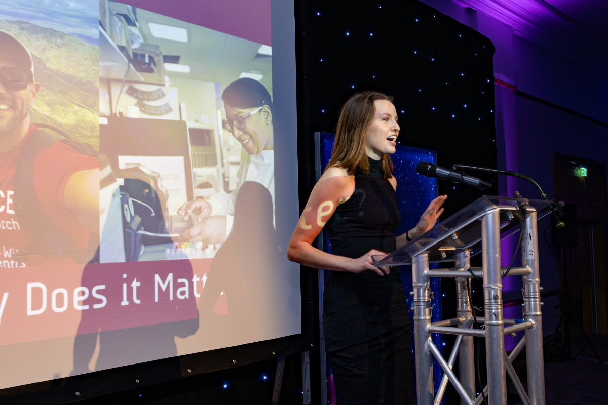 Liberty Harrison, Interim CEO, stood on stage and speaking at a gala.