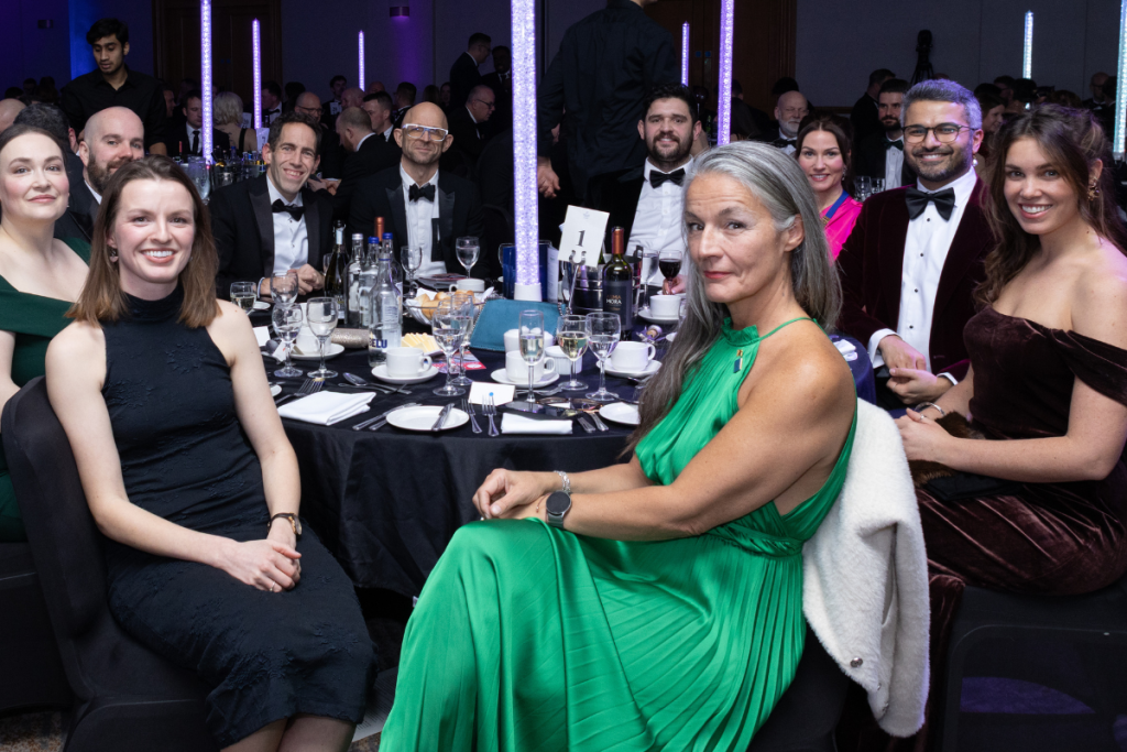 A group of people sat at a gala, smiling at the camera.