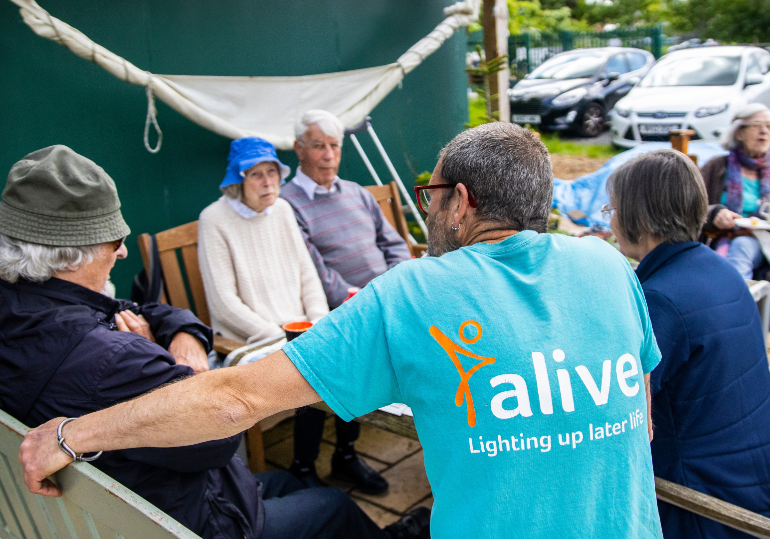 People are sat around a table at the Alive Allotments Dementia Friendly Garden.