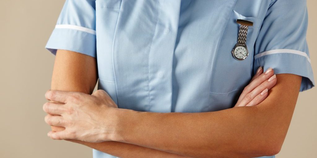 Torso of a nurse with her arms crossed.