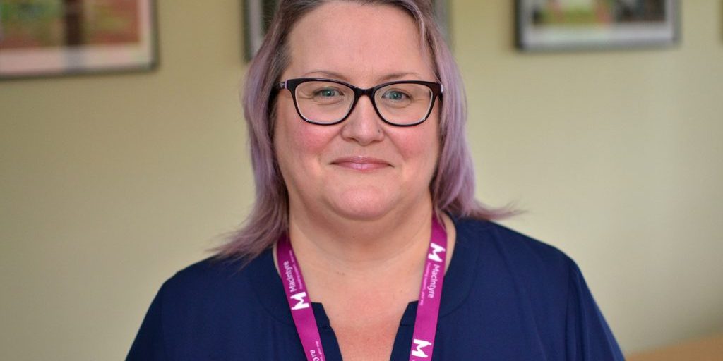 A head shot of a woman wearing glasses and a landyard.