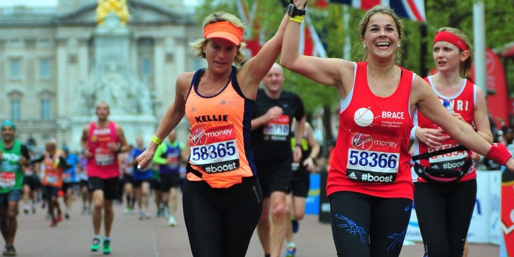 Two women holding hands and running towards the end of the London Marathon
